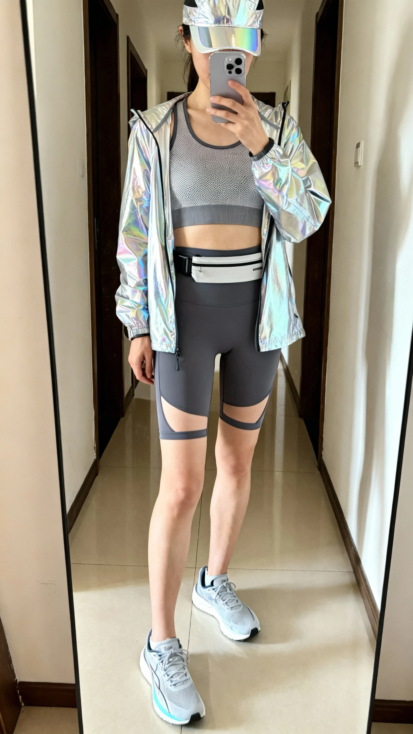 iPhone mirror selfie of a woman in a running capsule: reflective windbreaker, breathable mesh tank, high-waisted run shorts with built-in liner, lightweight running shoes, slim running belt, and a reflective cap, face not visible, cropped at shoulders, hallway full-length mirror, bright morning light, iPhone photo quality.