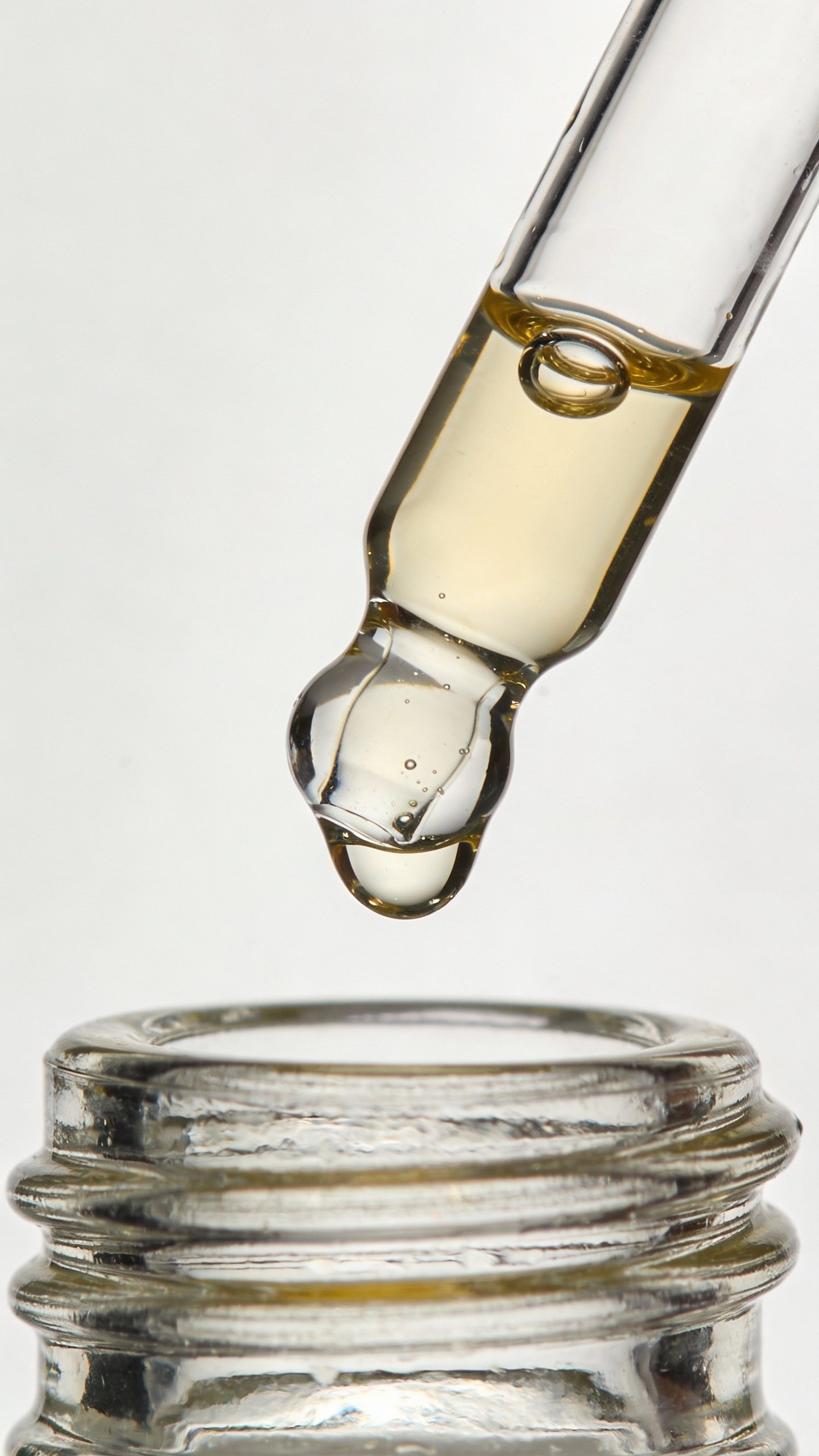 closeup of vitamin C serum dropper over glass bottle