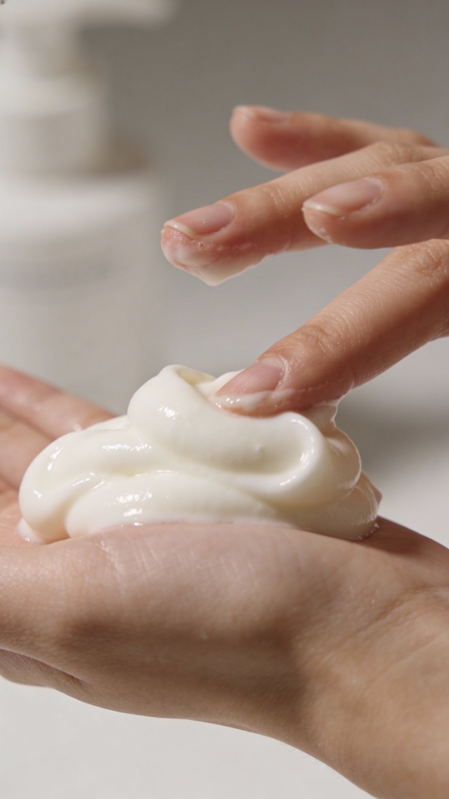 closeup of fragrance-free creamy cleanser on fingertips, studio lighting