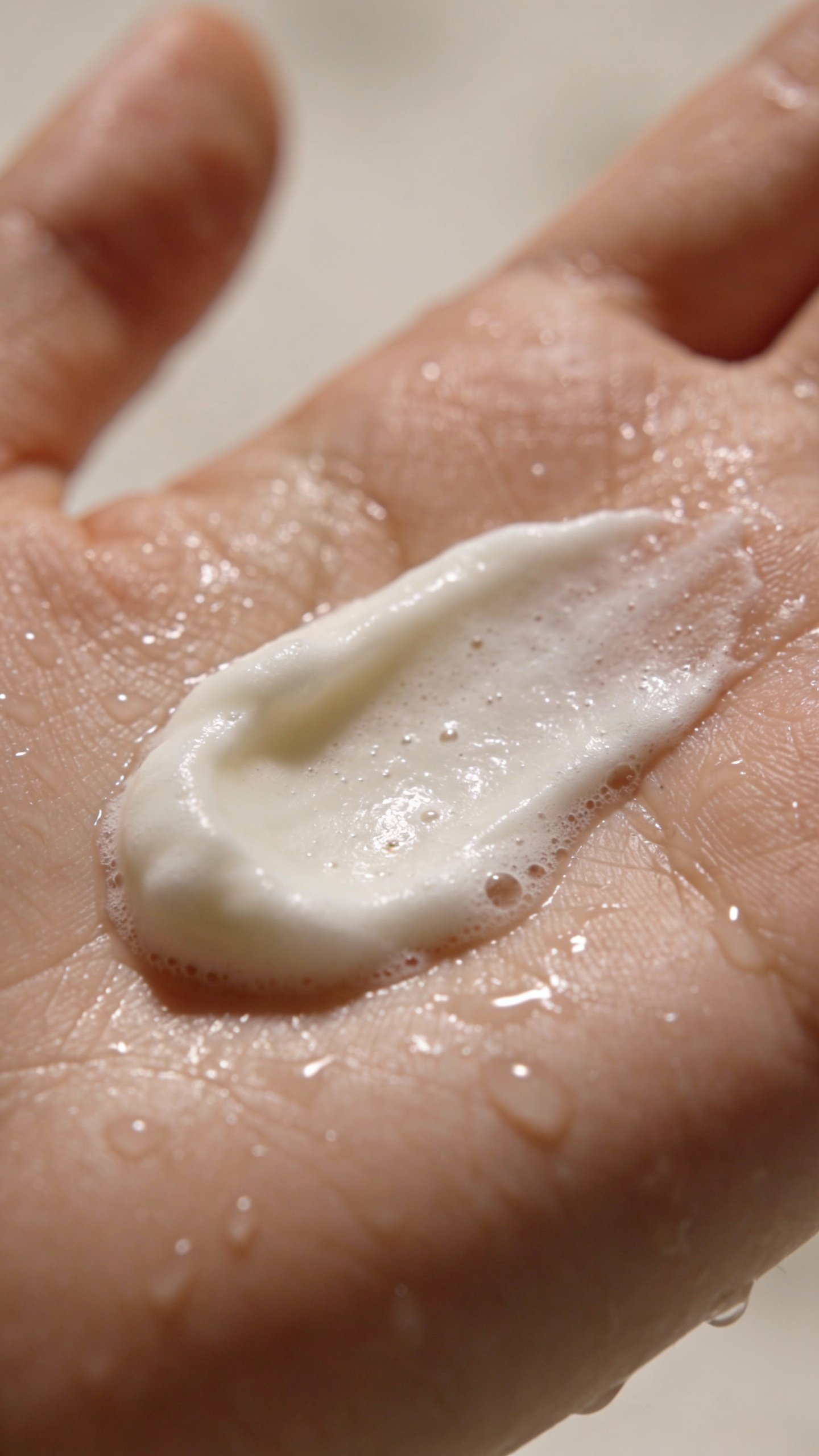 closeup of creamy low-foam cleanser on wet palm