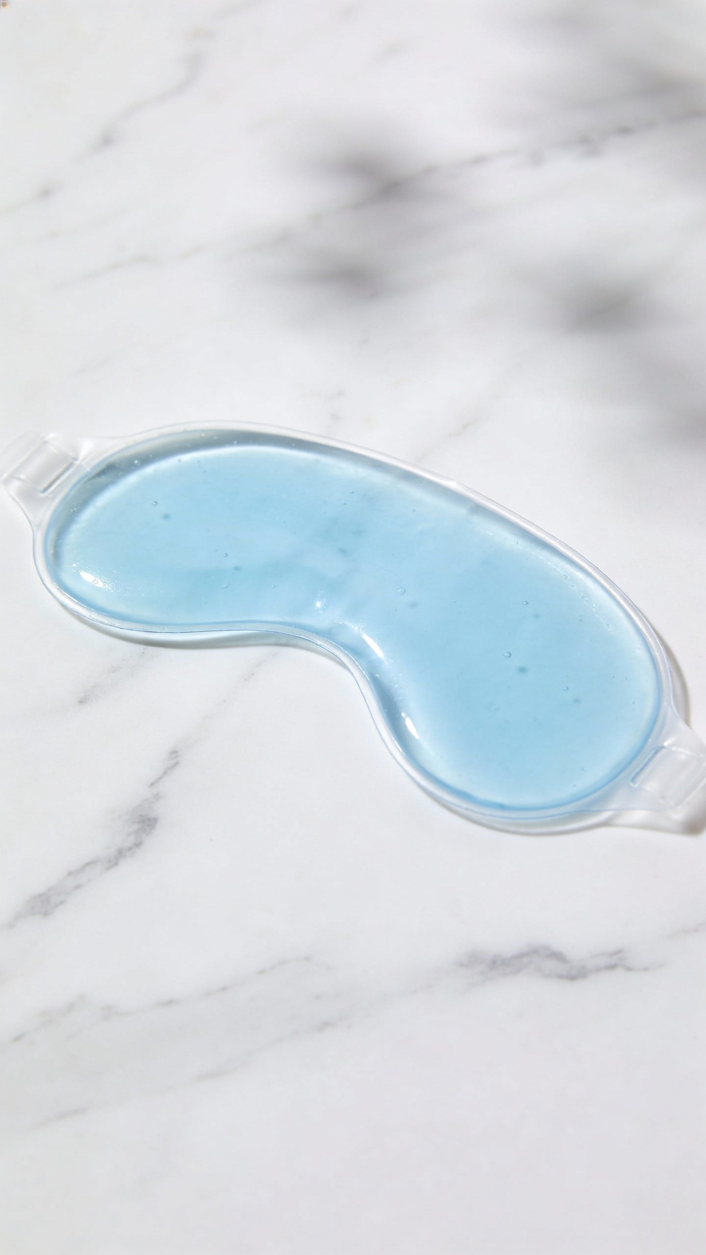 single reusable gel eye mask on white marble surface