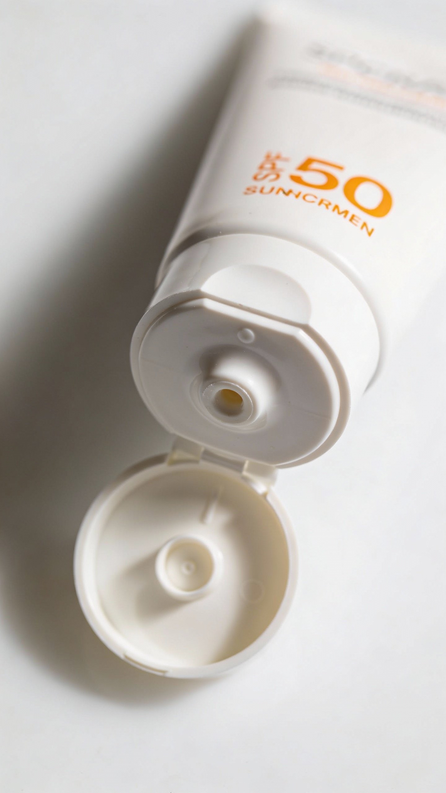 closeup of SPF 50 sunscreen tube with pump on white
