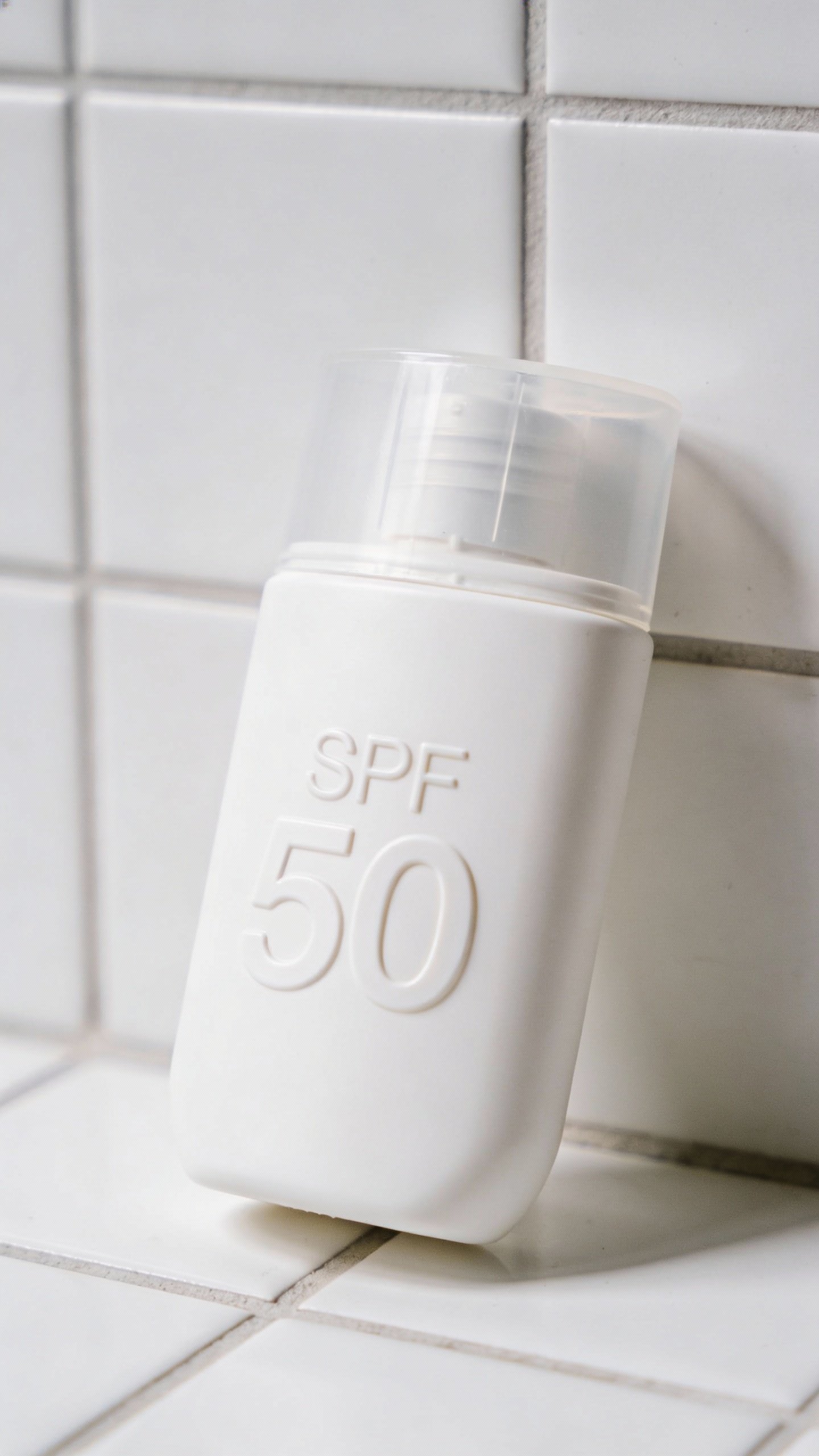 closeup of sunscreen bottle with SPF 50 on white tile