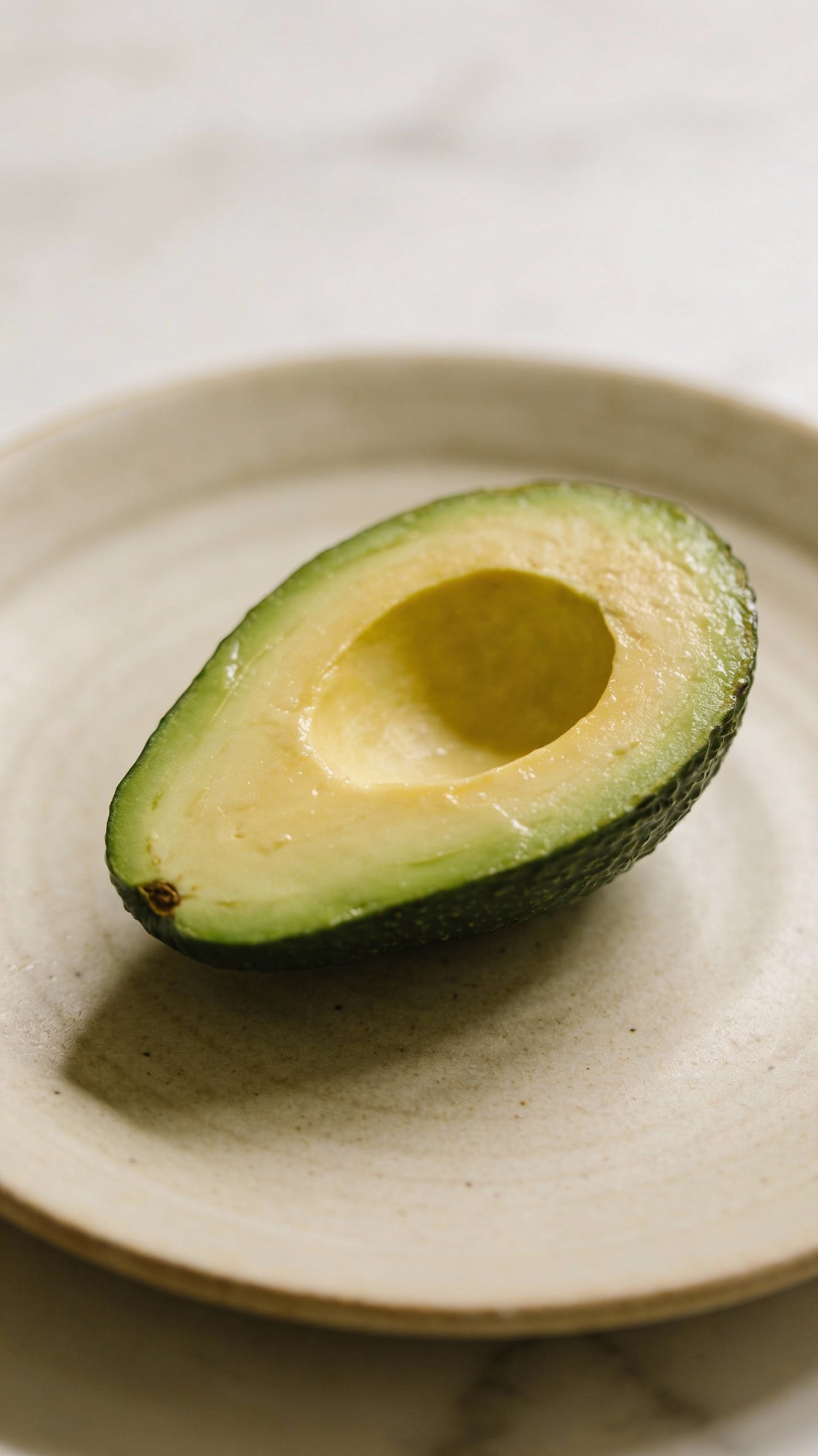single halved avocado on a neutral ceramic plate
