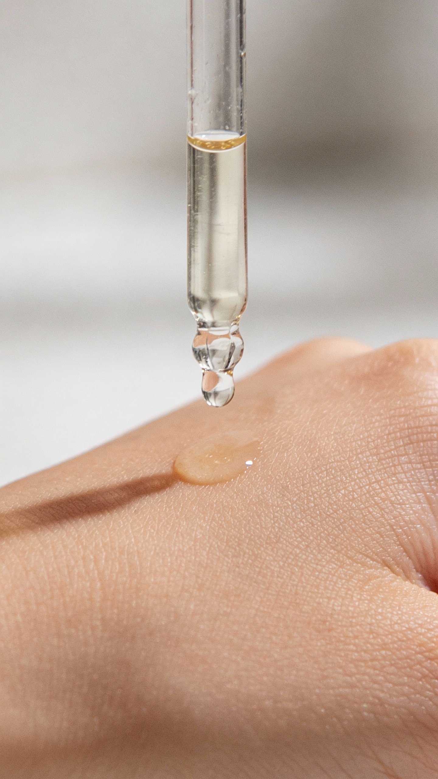 closeup of niacinamide serum dropper above clean cheek