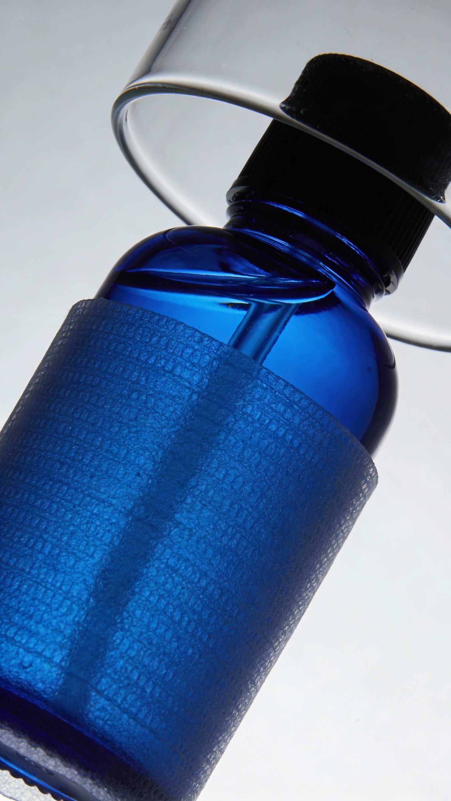 Blue cobalt bottle labeled “Vitamin C Toner” under UV-protective sleeve closeup