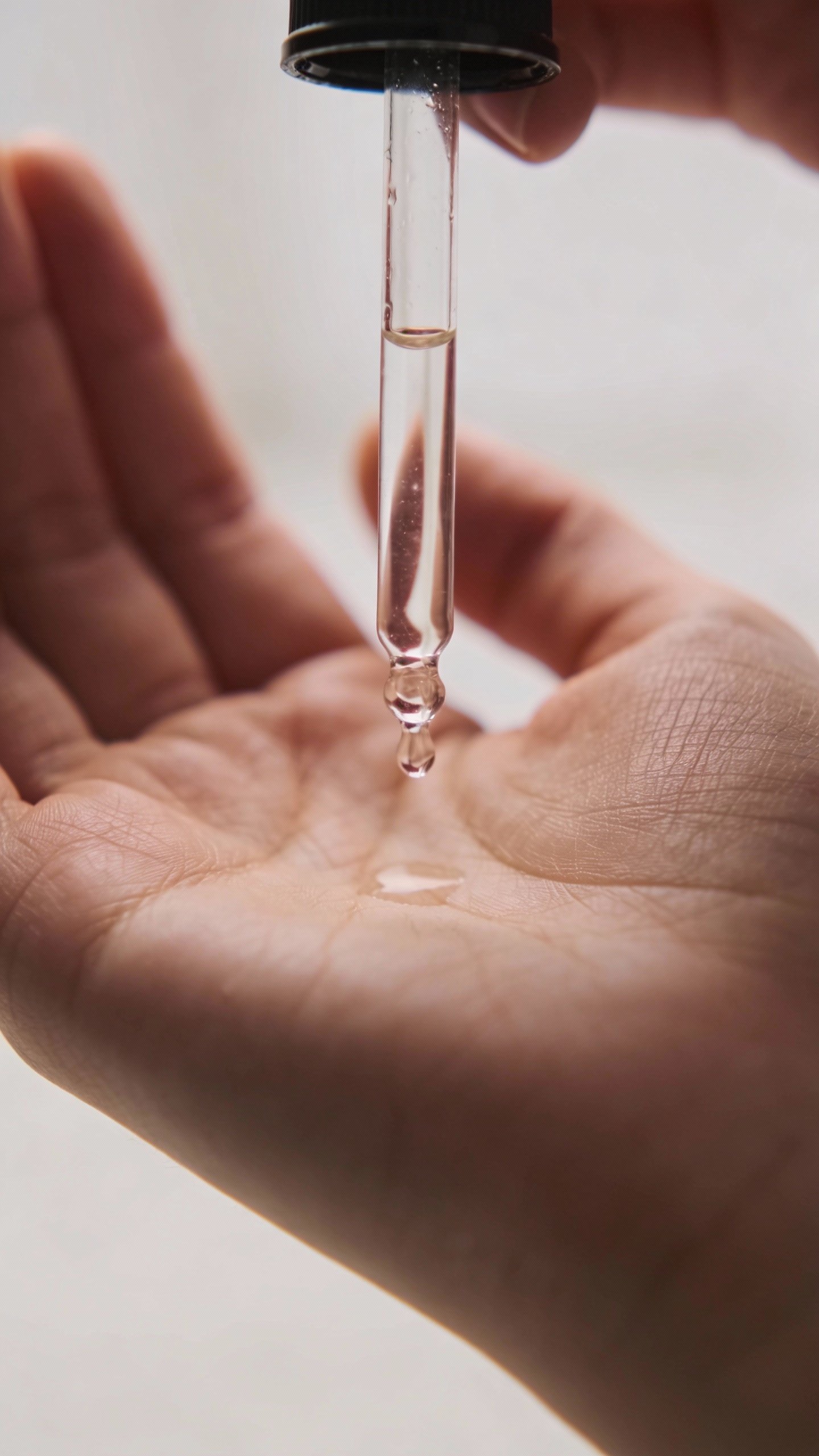 closeup of salicylic acid serum dropper over palm