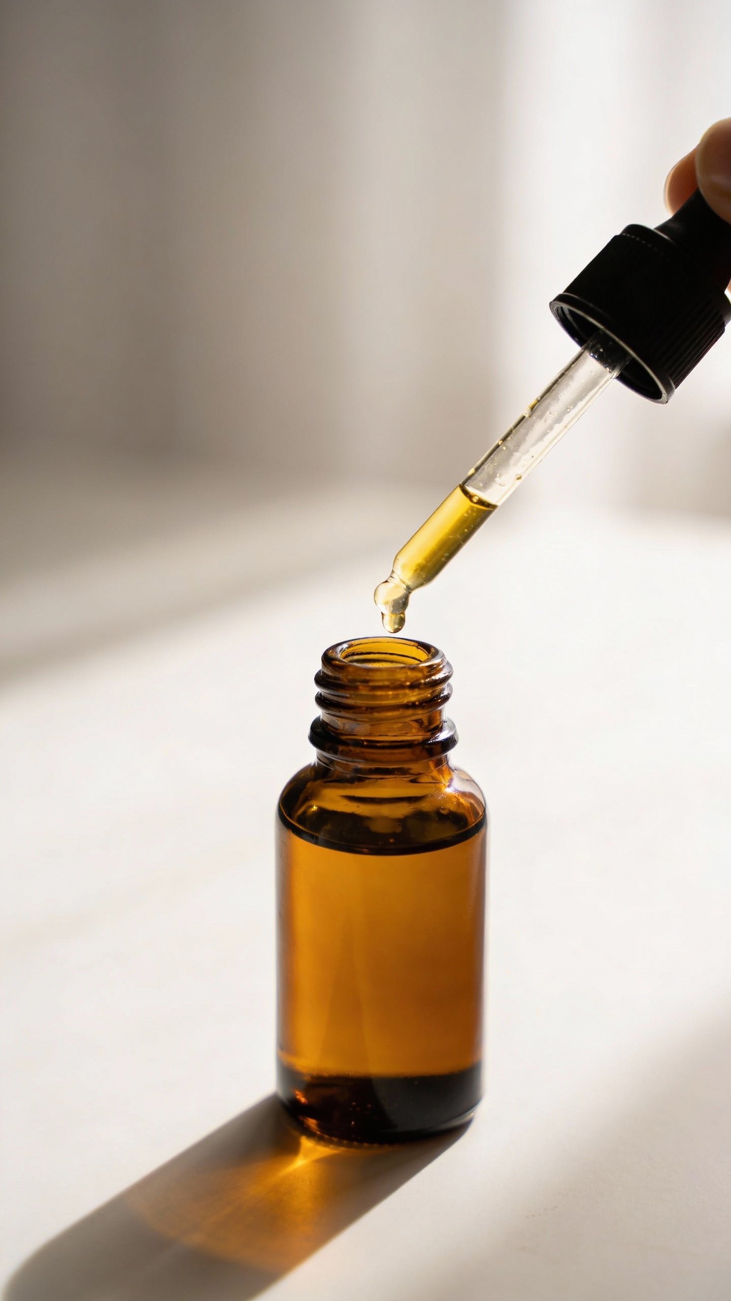 single amber facial oil bottle with dropper, soft backlight