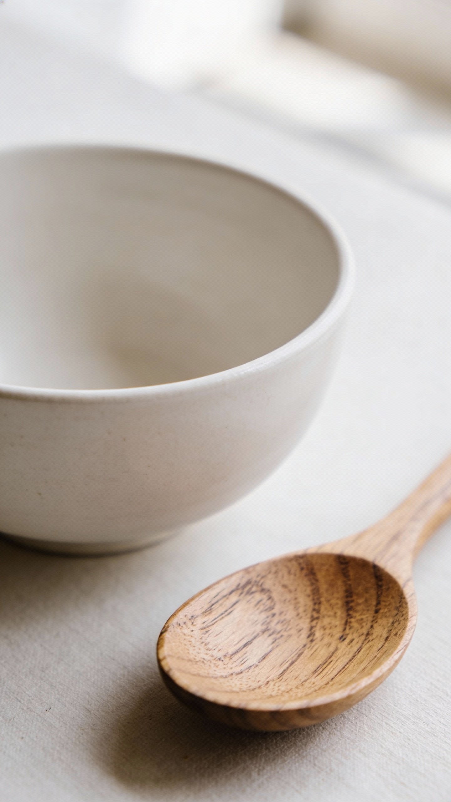 Single ceramic bowl of white kaolin clay with wooden spoon