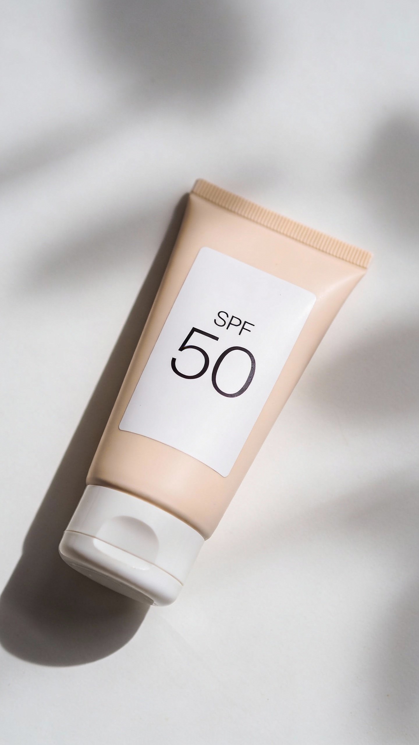single sunscreen tube, white label, SPF 50, soft daylight