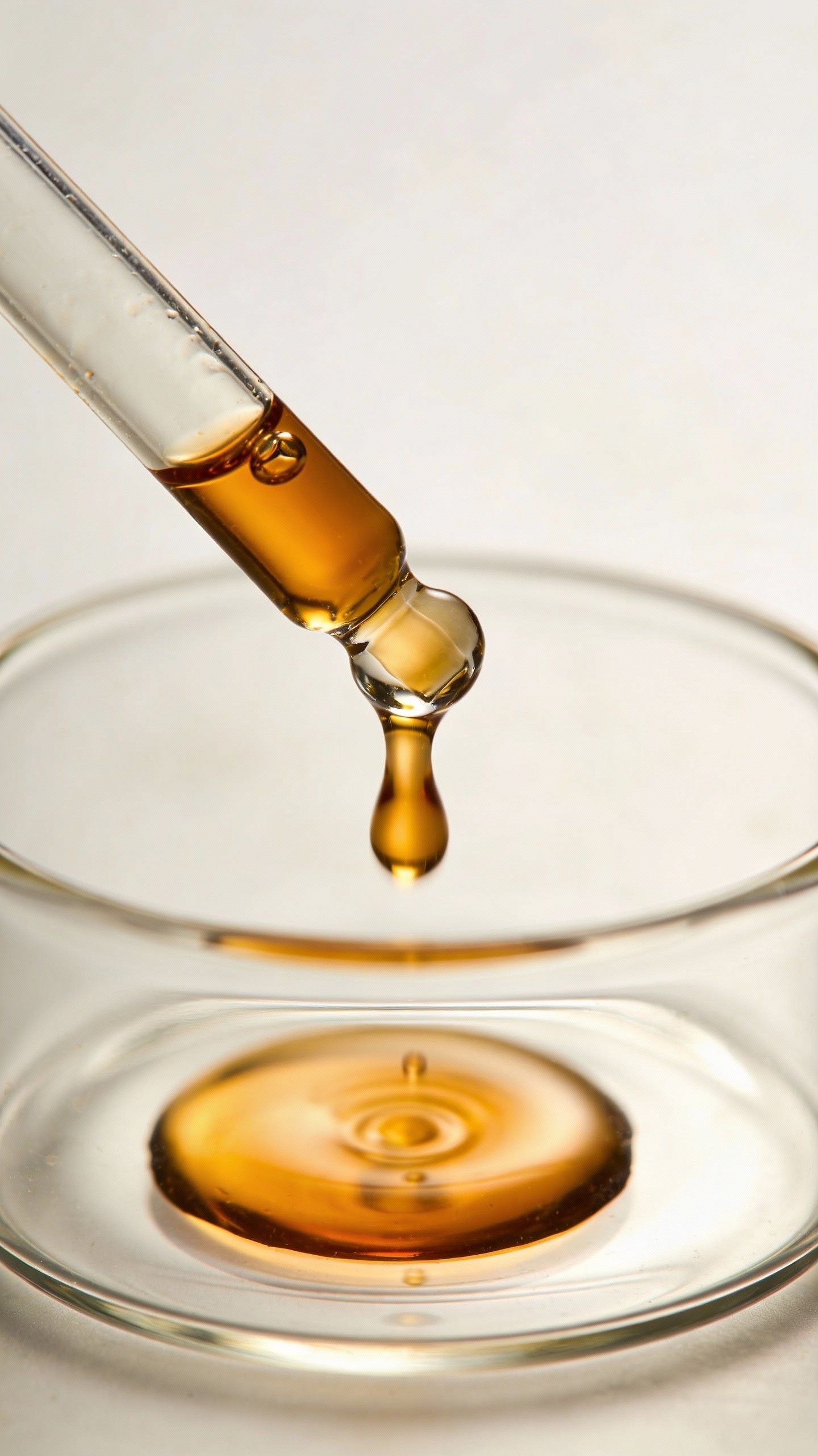 glass dropper dispensing rosehip oil into small beaker