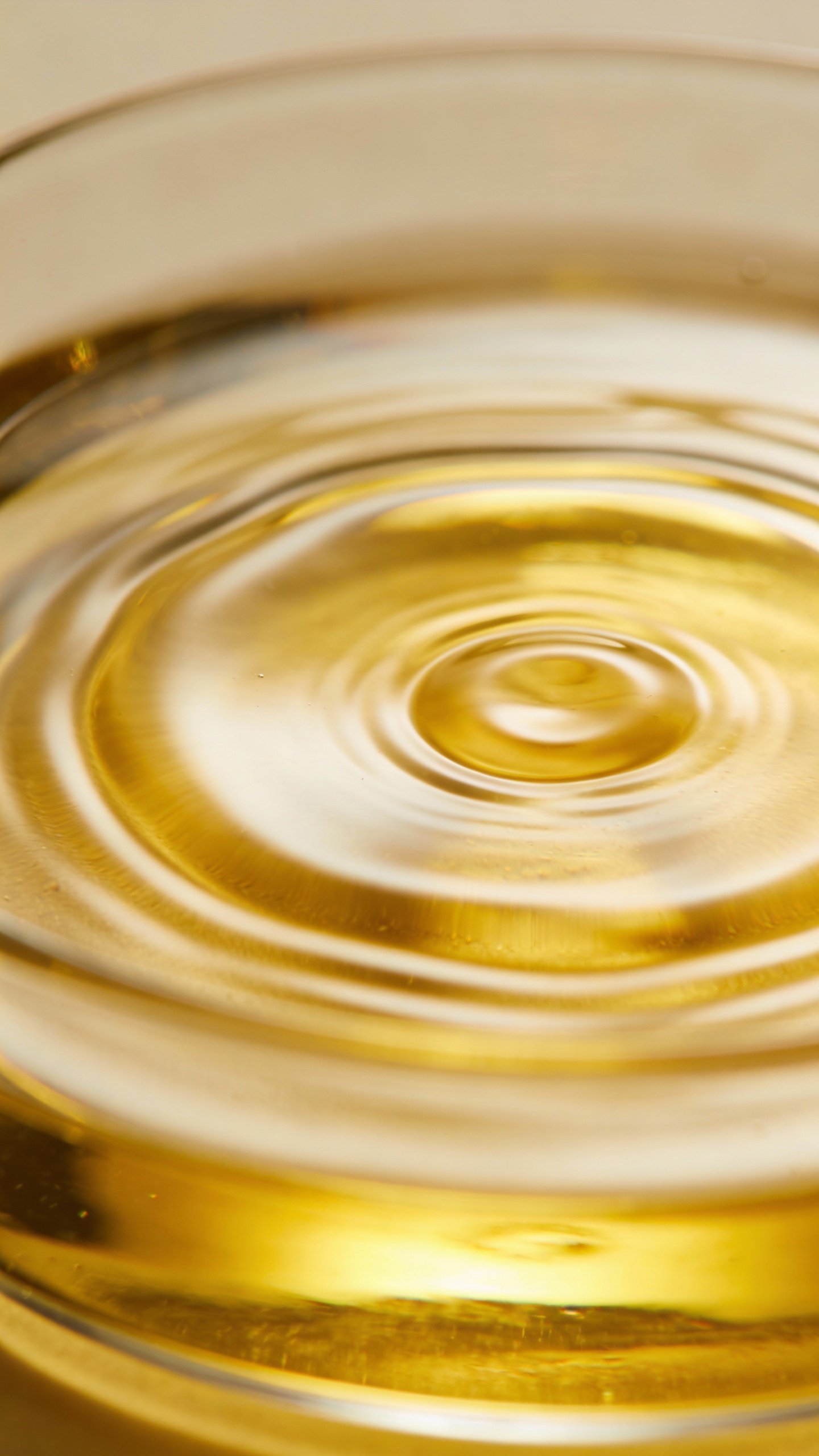 Closeup of golden jojoba oil rippling in clear dish