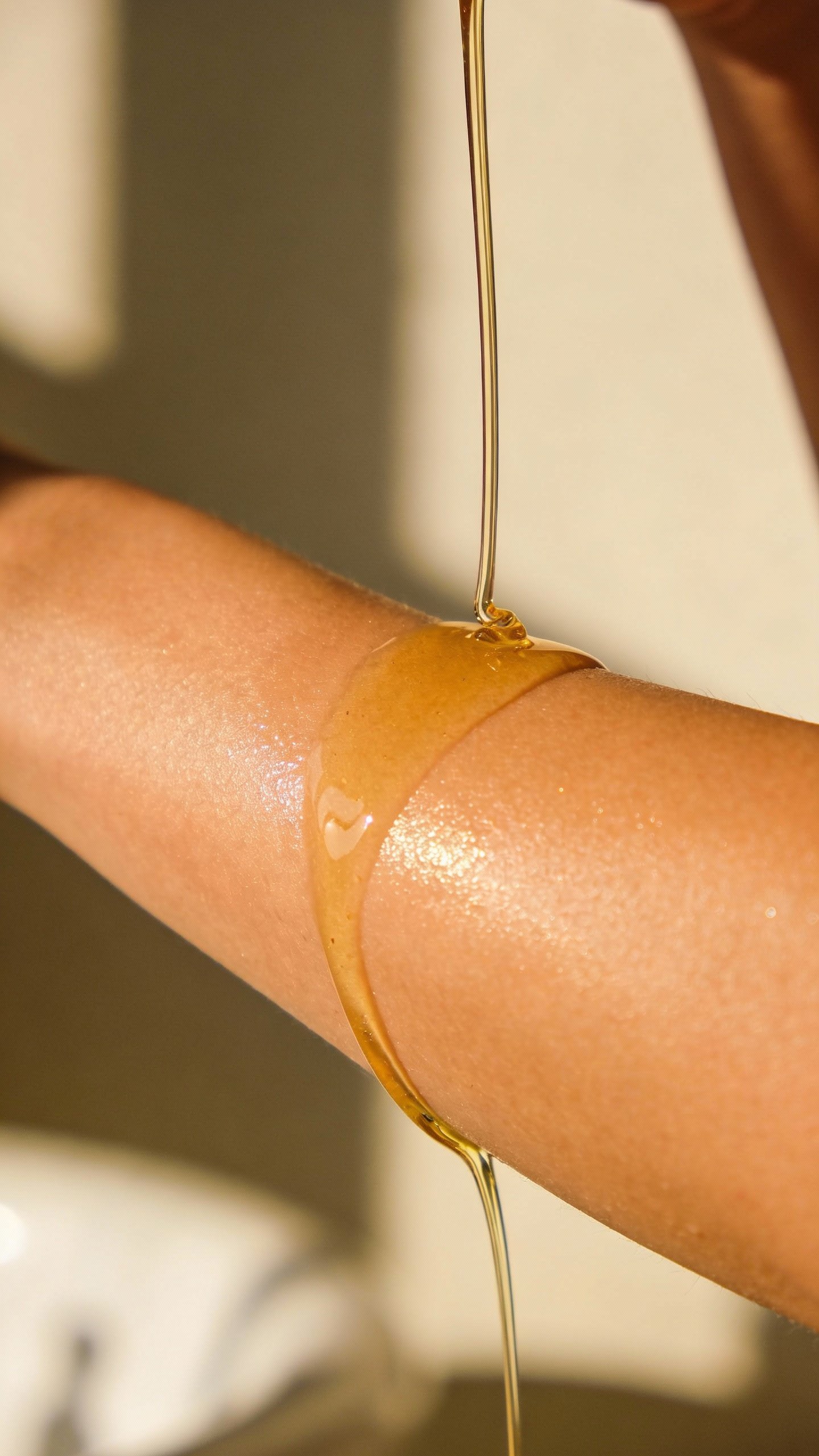 Freshly poured body oil on woman’s forearm, soft glow