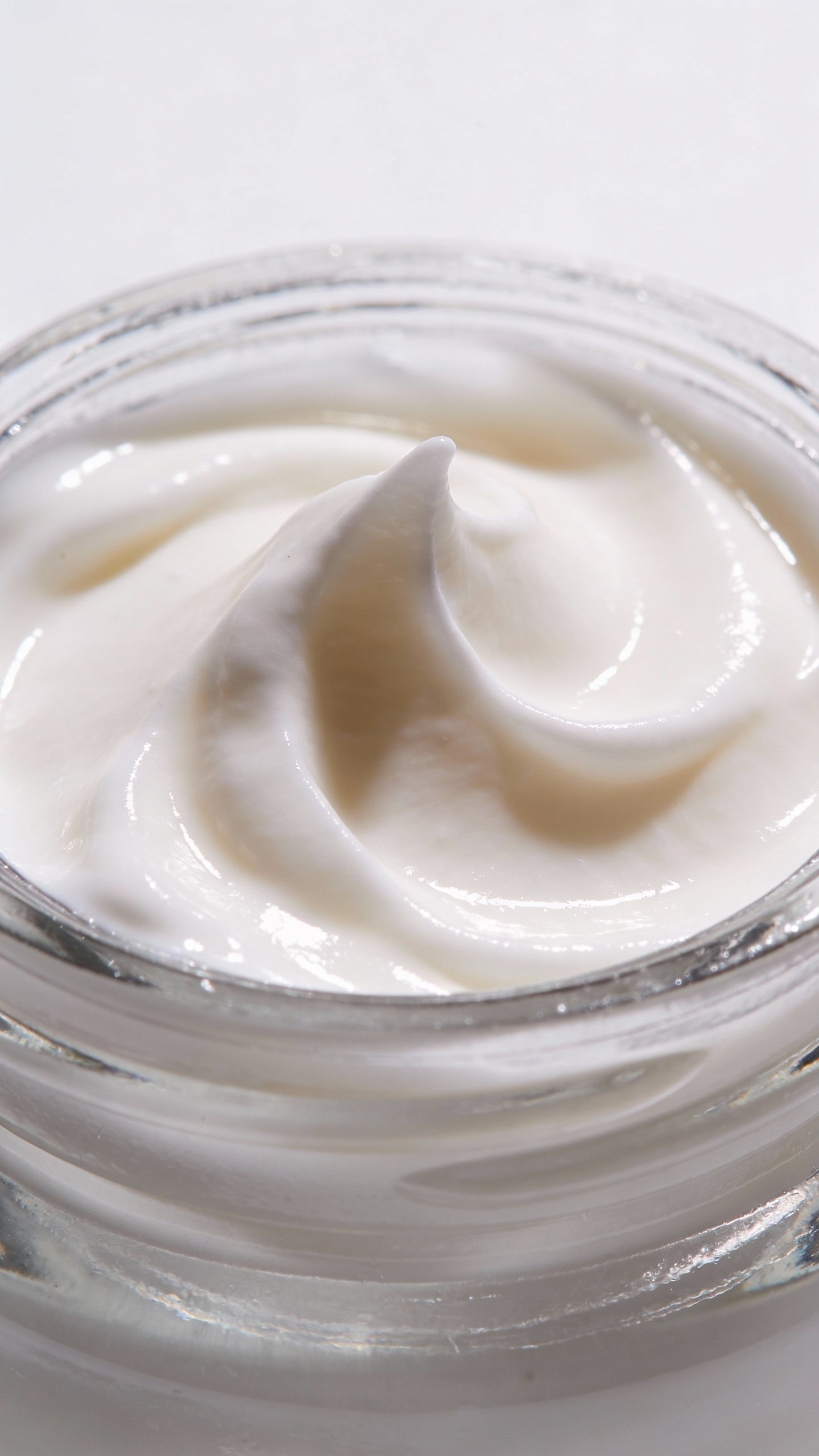 clear glass jar of under-eye cream, macro, white background