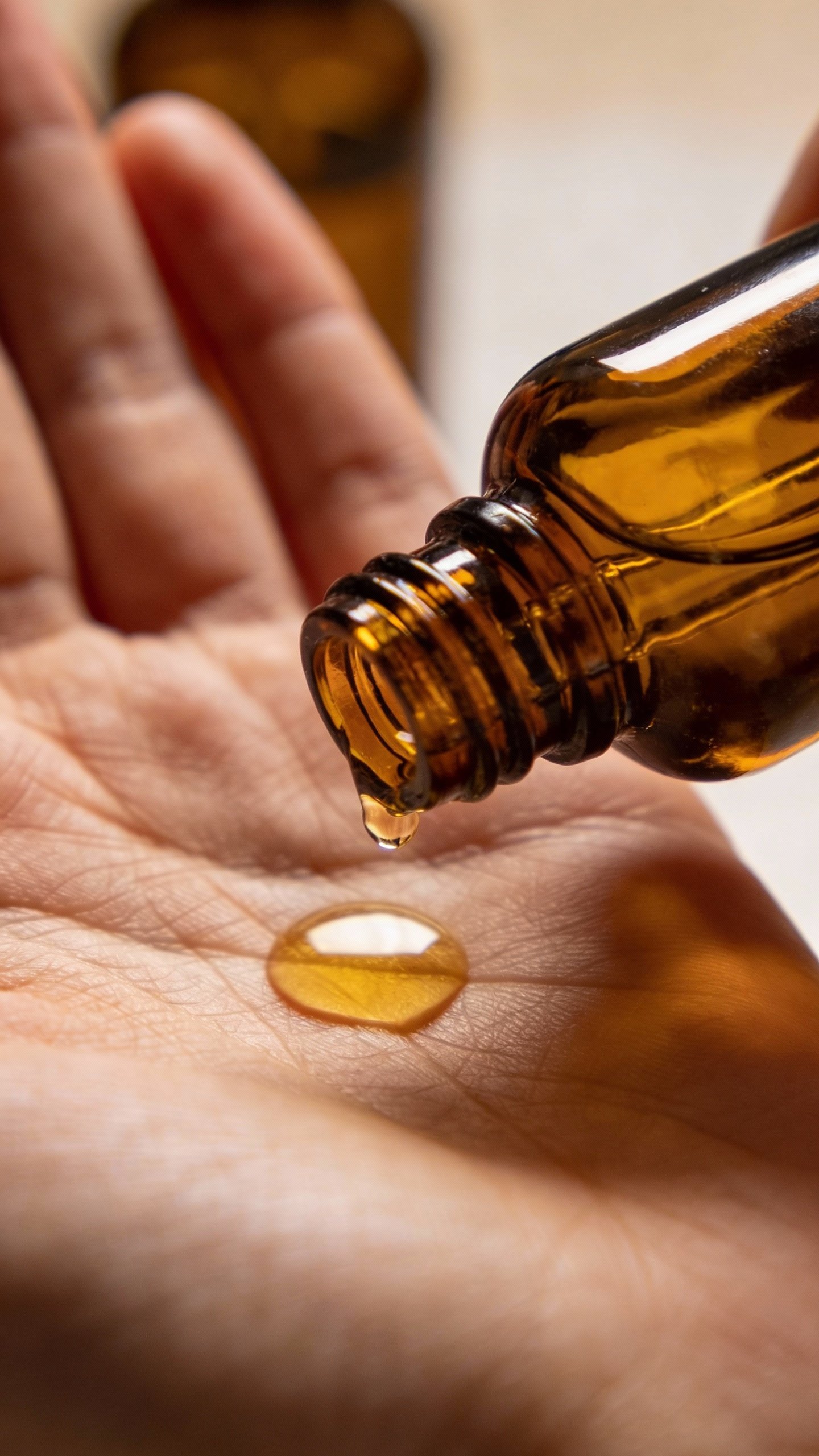 closeup amber dropper bottle dispensing oil onto palm