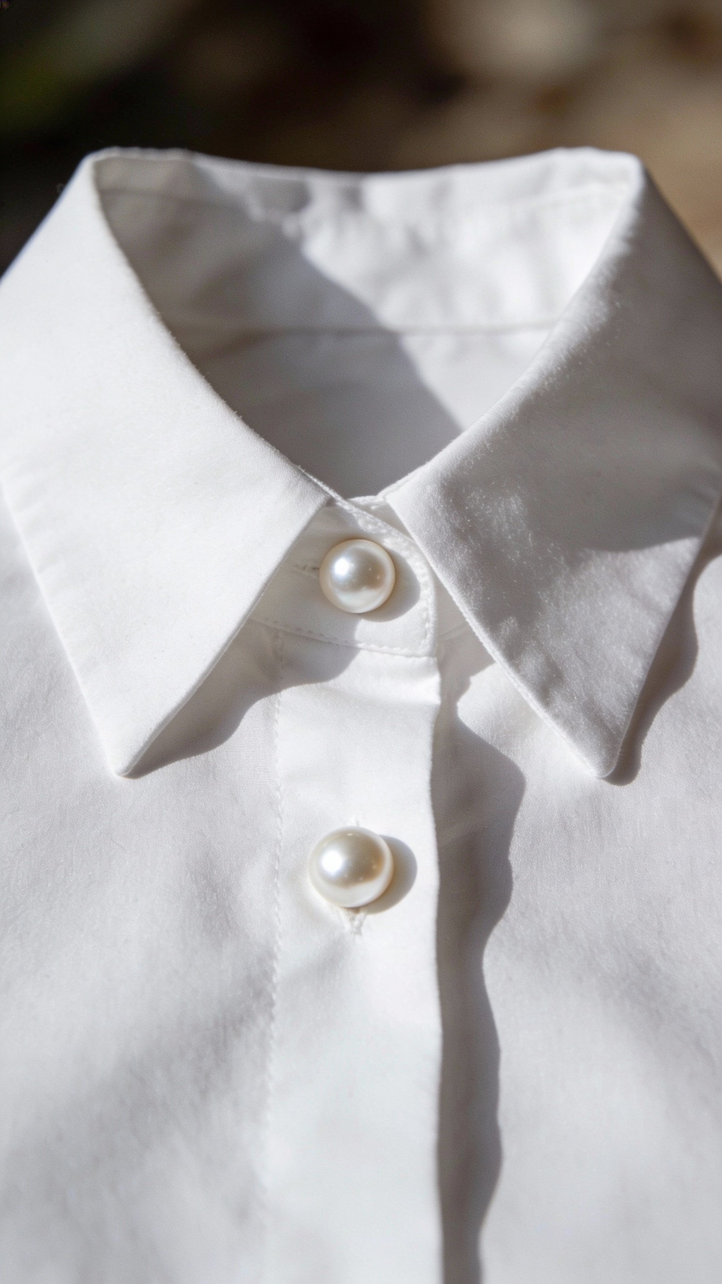 closeup of crisp white button-down collar with pearl buttons