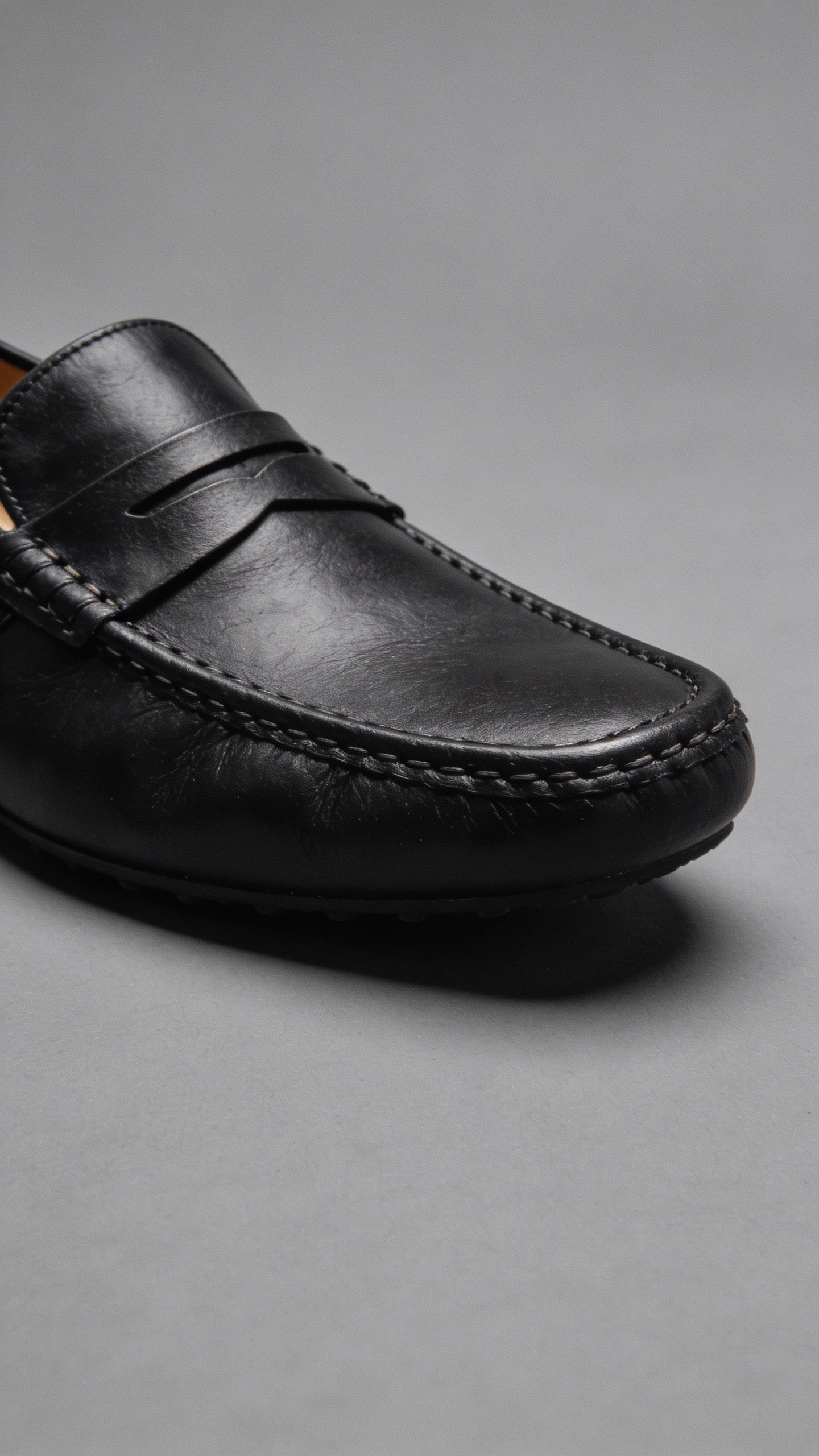 black leather loafers on gray backdrop, detail shot