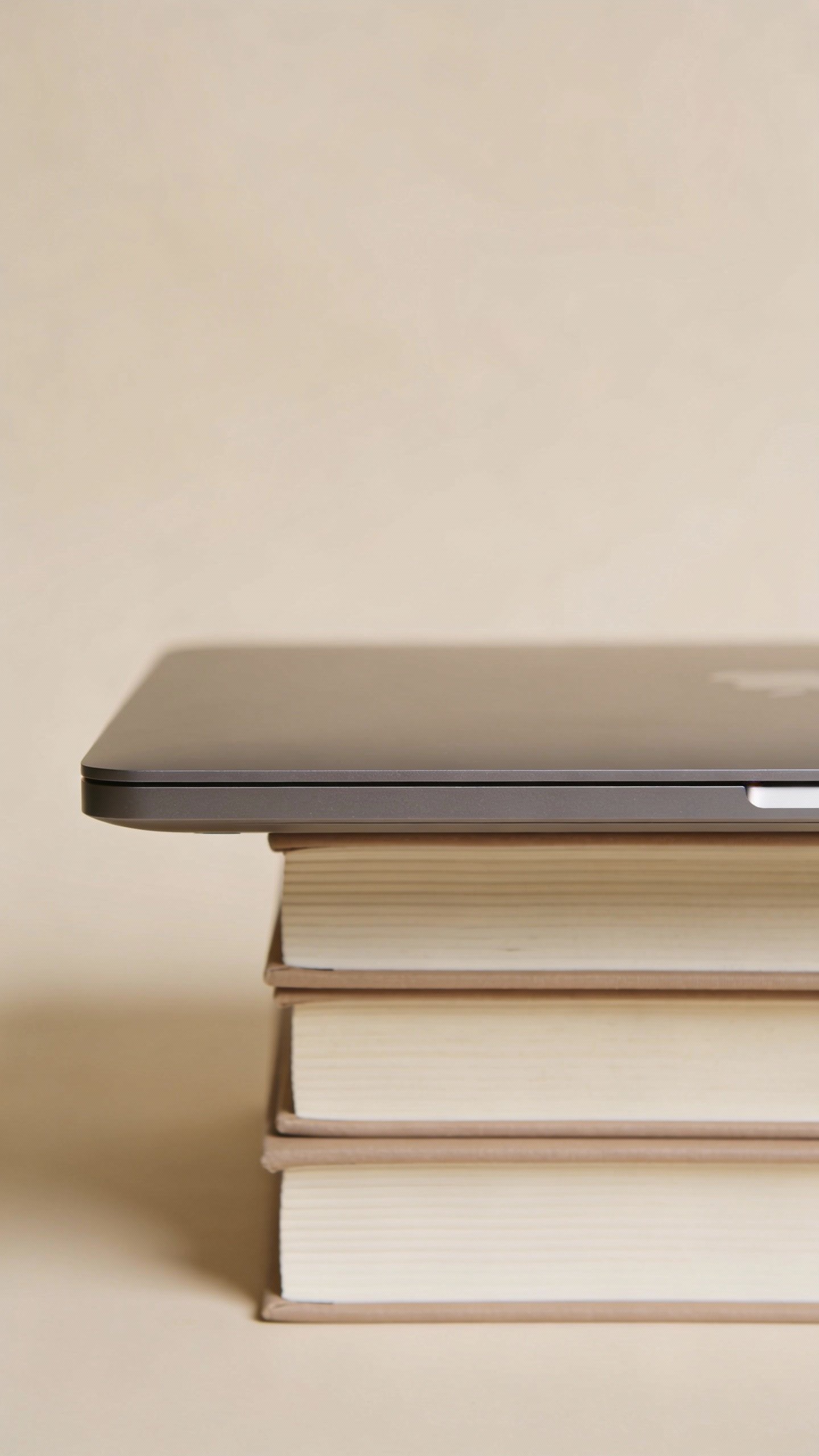 Single stack of books elevating laptop, neutral background