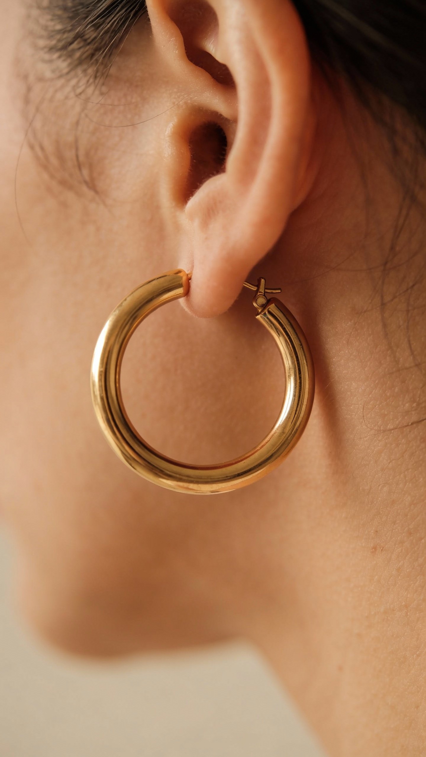 single oversized gold hoop earring, macro on lobe