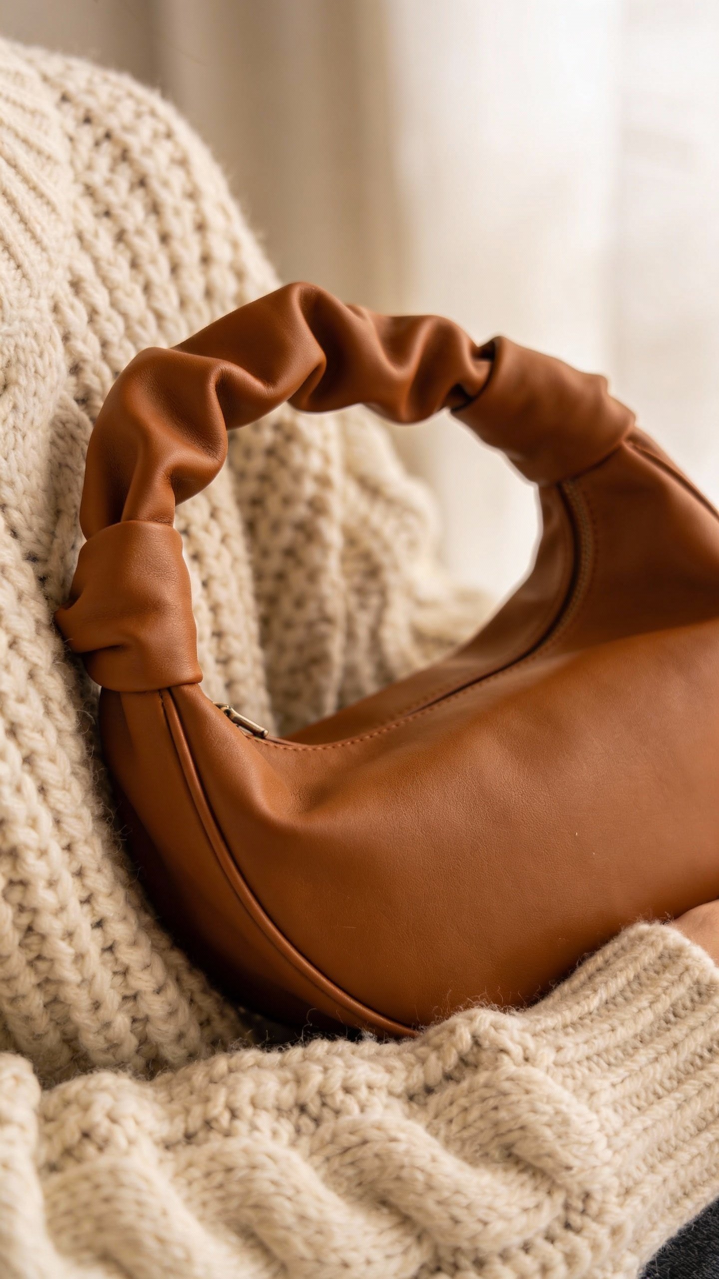 Slouchy caramel hobo bag against chunky knit sweater