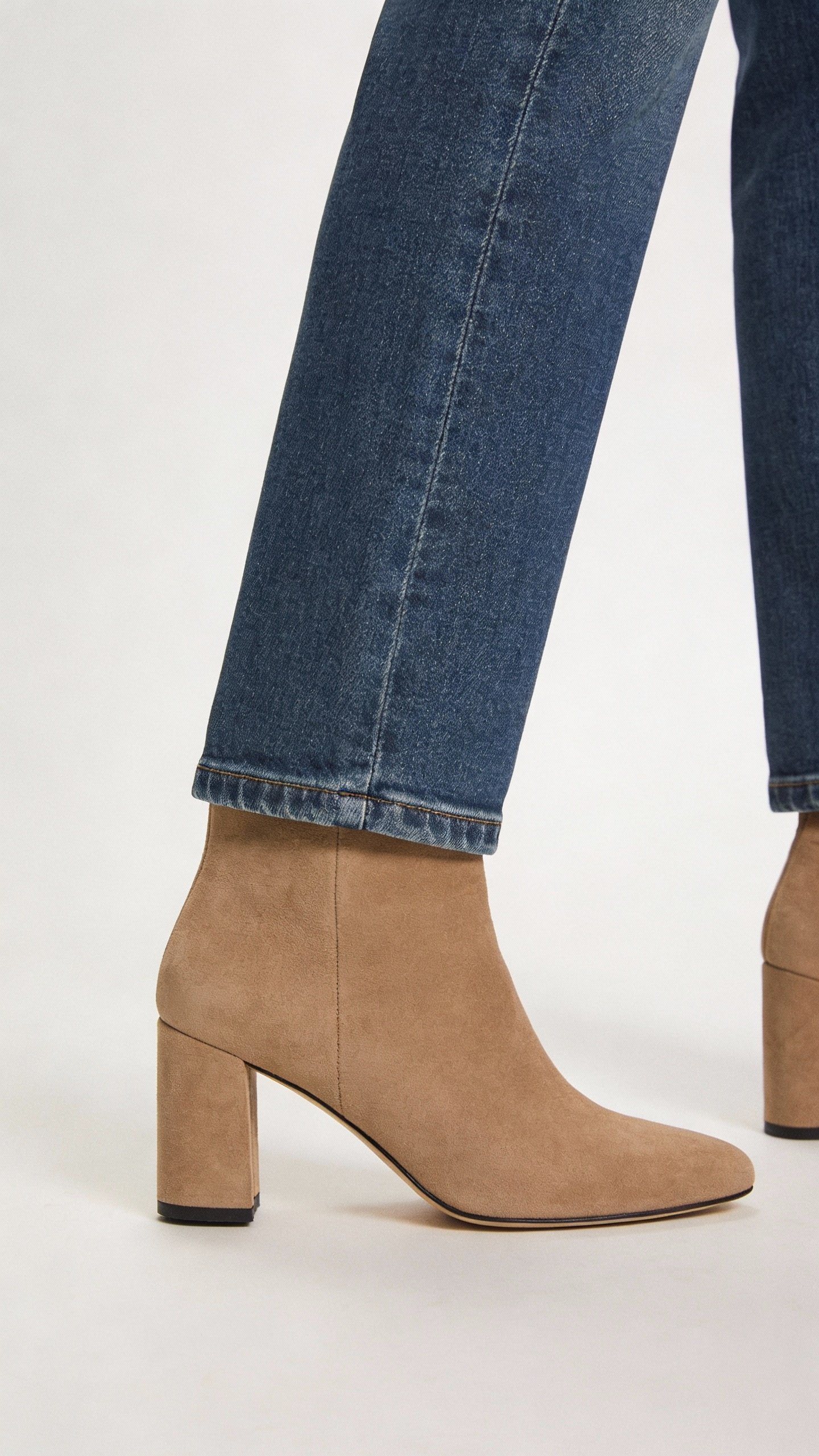 tailored high-waisted jeans hemmed to ankle boots, studio closeup