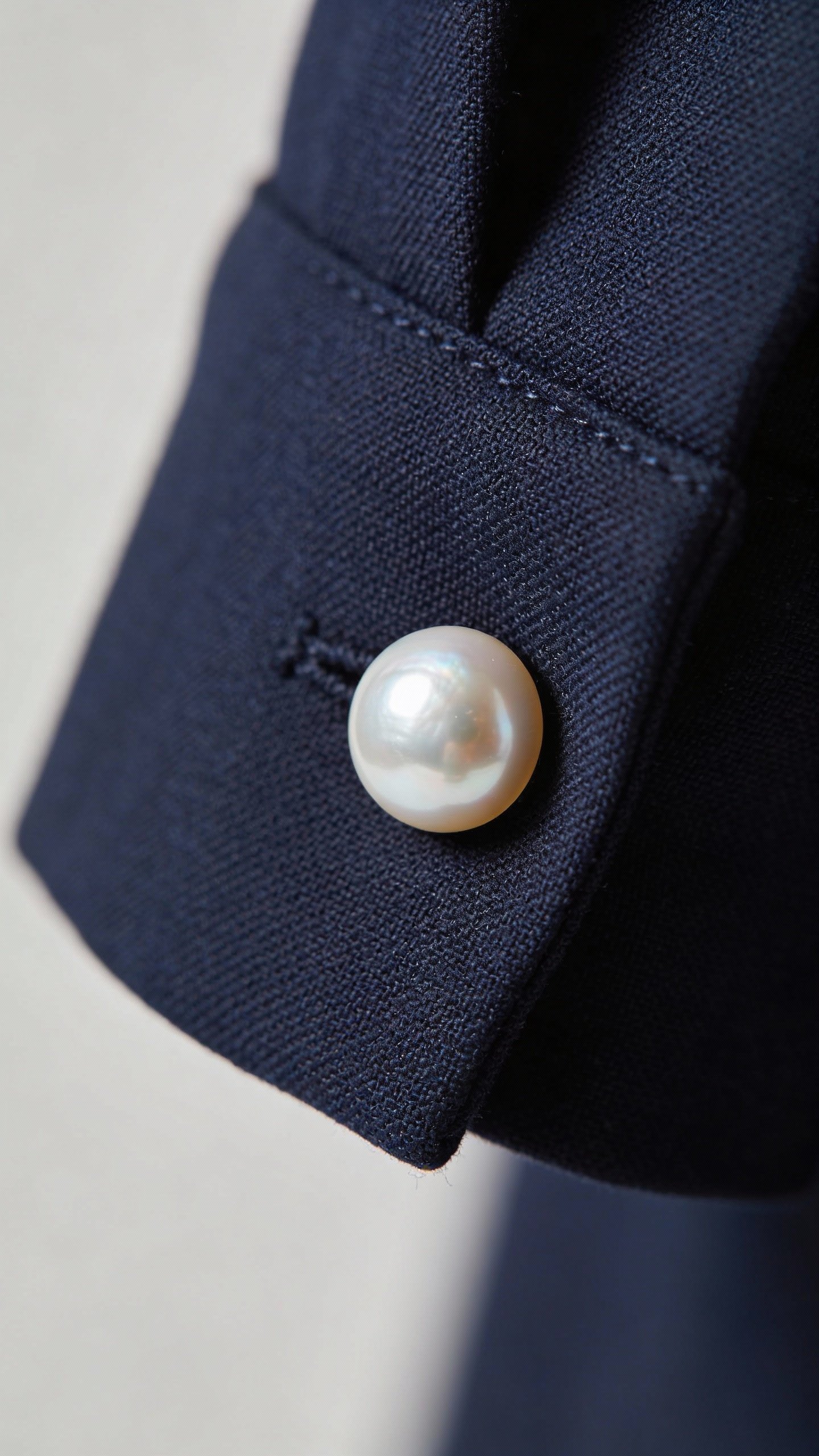 single pearl button replacement on navy blazer cuff, macro shot