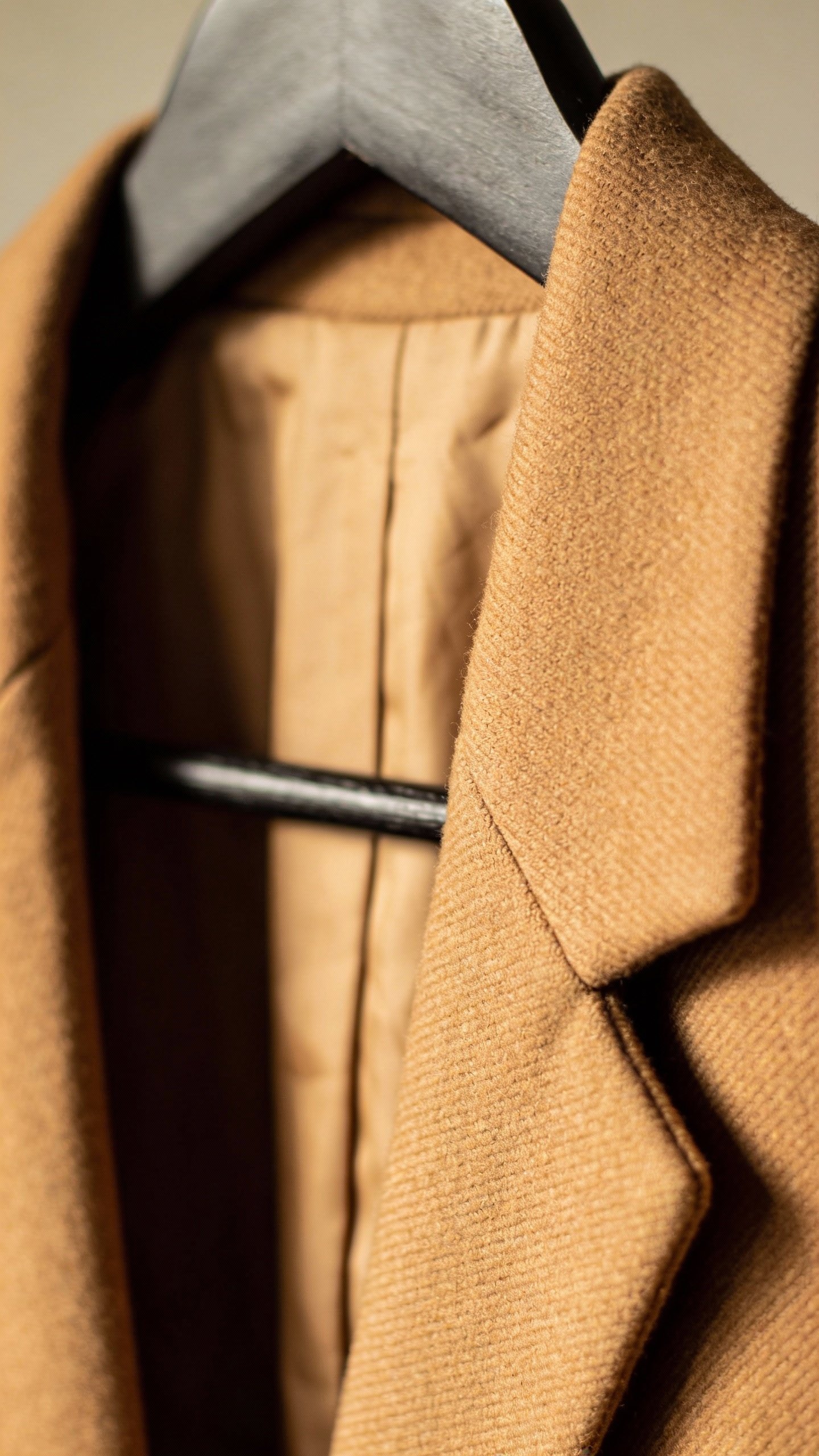 closeup of camel wool blazer on matte black hanger