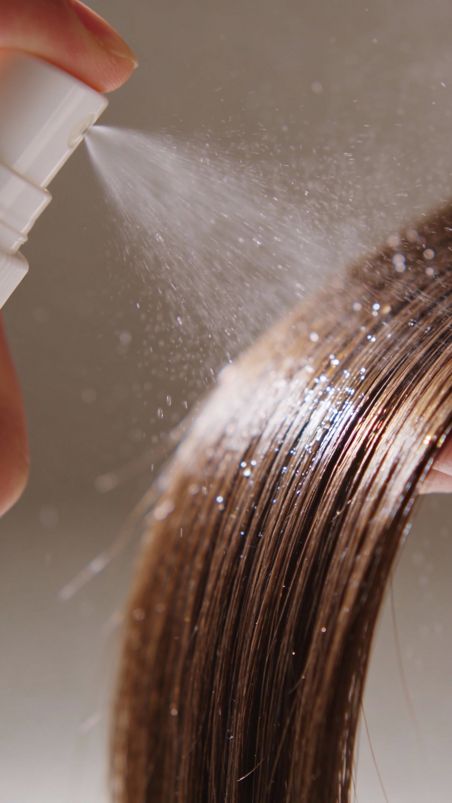 misting heat protectant onto a single hair section, macro