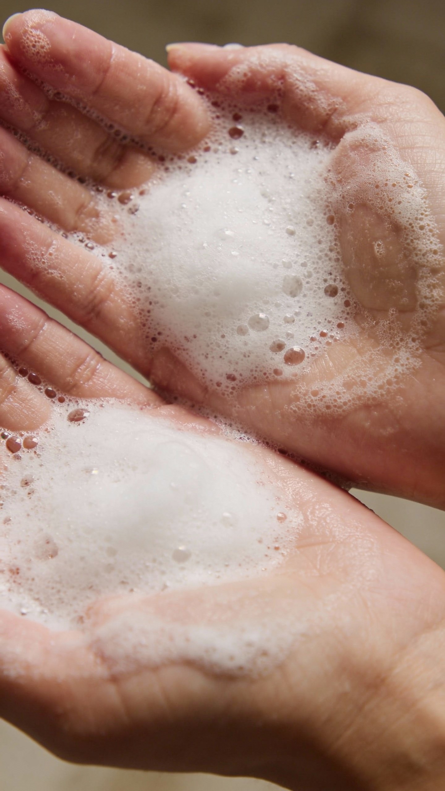 Emulsified shampoo lather in palms, studio macro shot