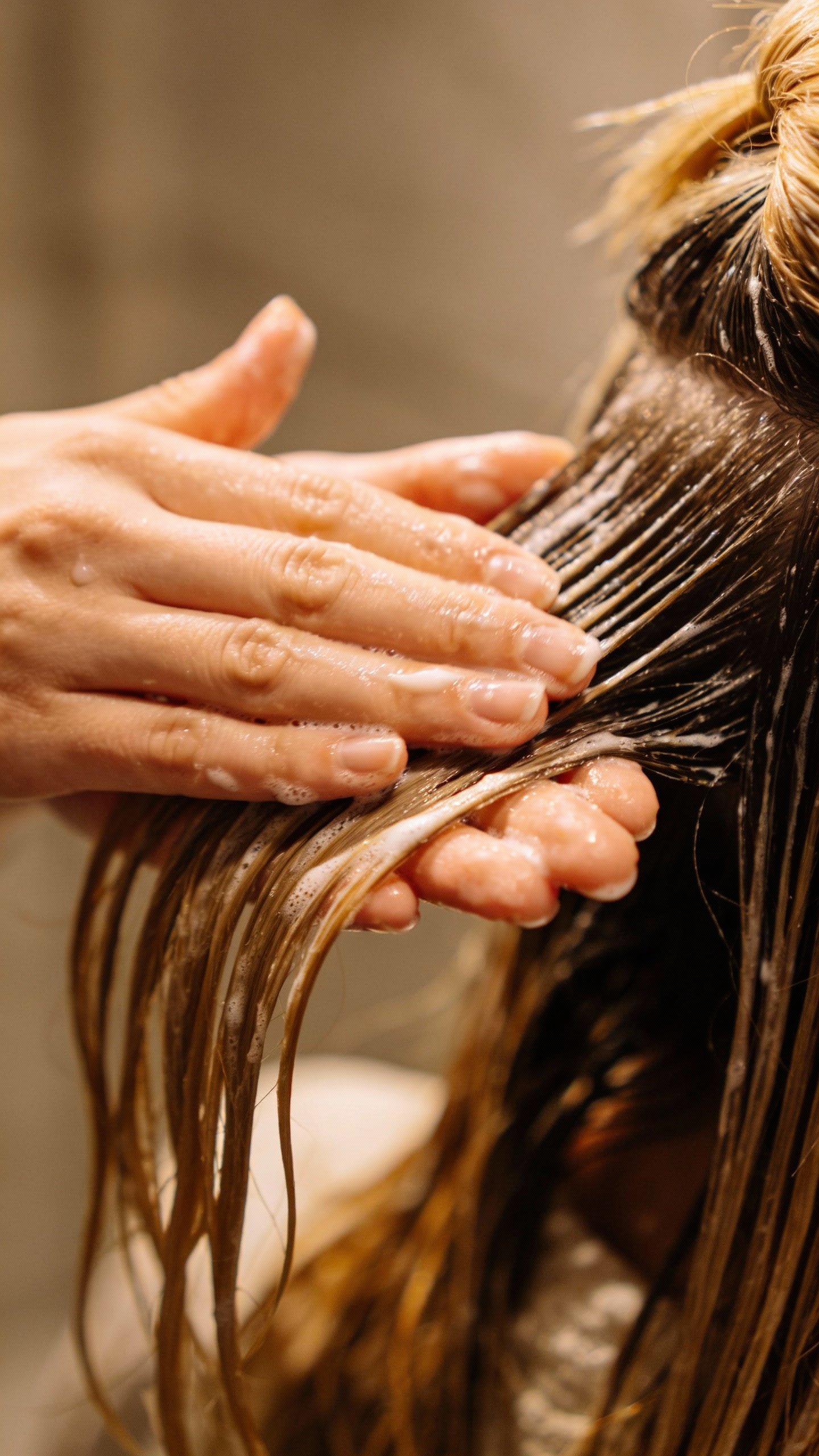 closeup of hand applying conditioner to hair mid-lengths only